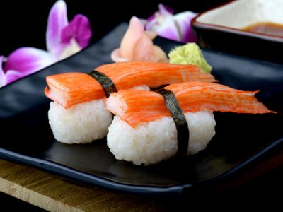 Crab stick sushi or Japanese kani sushi set on black plate with wasabi and sushi sauce with flash lighting.